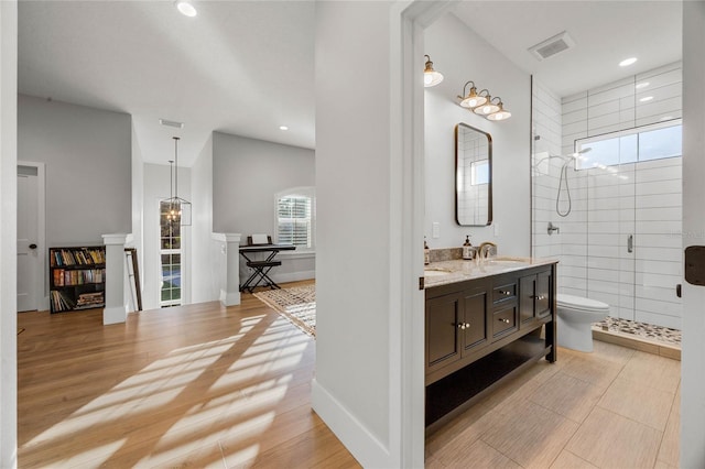 full bath featuring wood finished floors, visible vents, double vanity, a sink, and a shower stall