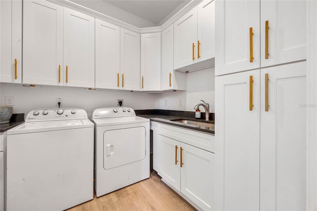 laundry room featuring washer and dryer, cabinet space, light wood-style floors, and a sink