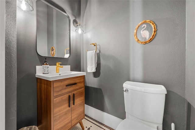 bathroom with toilet, vanity, and a textured wall