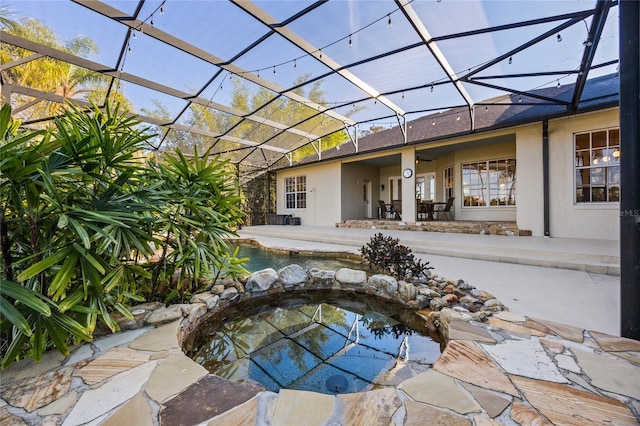 view of swimming pool featuring glass enclosure, a jacuzzi, and a patio area