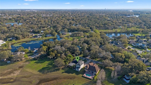 birds eye view of property featuring a forest view, a water view, and a residential view