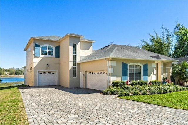 view of front of home featuring stucco siding, decorative driveway, and a water view