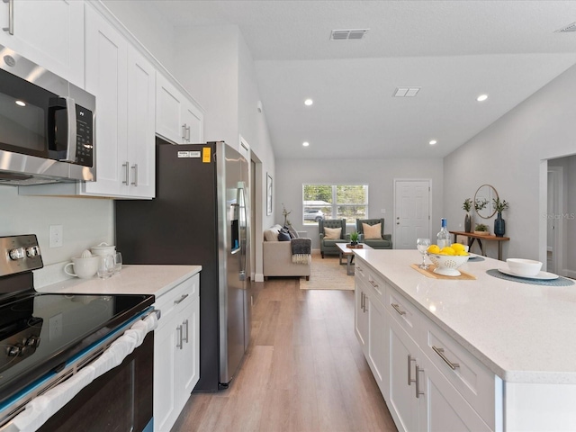 kitchen featuring appliances with stainless steel finishes, light countertops, open floor plan, and white cabinets