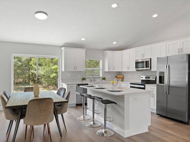 kitchen featuring stainless steel appliances, a center island, light countertops, and white cabinetry