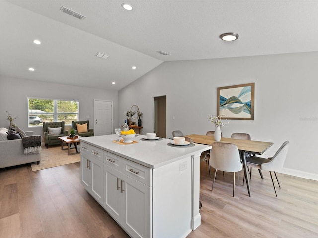 kitchen featuring white cabinets, light wood-style flooring, visible vents, and a center island