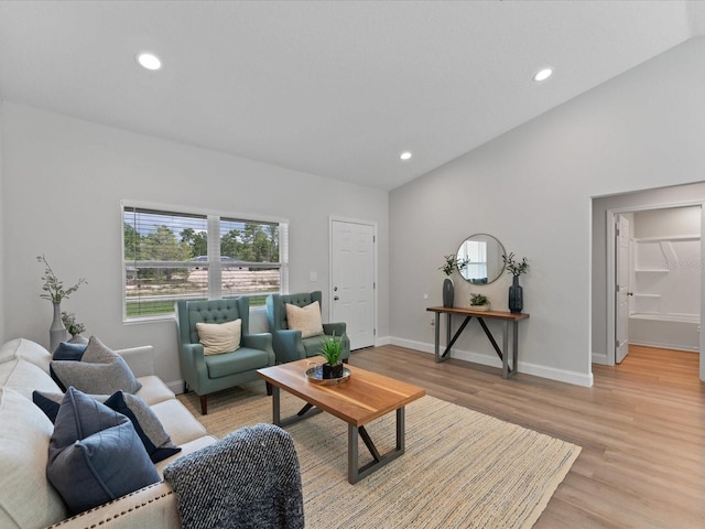 living room featuring lofted ceiling, light wood-type flooring, baseboards, and recessed lighting