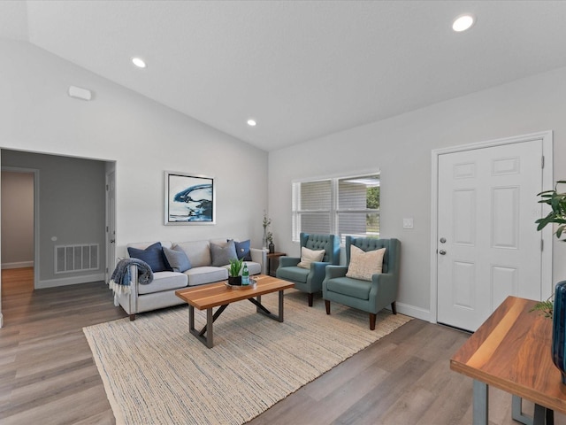 living area with lofted ceiling, visible vents, and light wood-style flooring