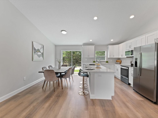 kitchen with appliances with stainless steel finishes, light wood-type flooring, light countertops, and white cabinetry