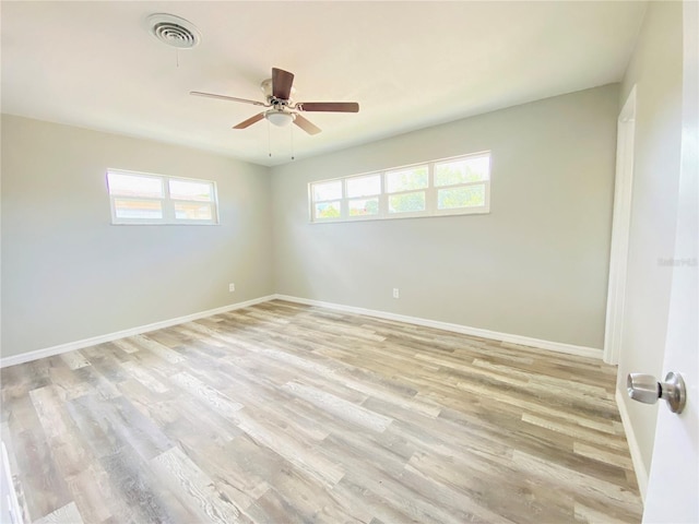 unfurnished room with a ceiling fan, light wood-type flooring, visible vents, and baseboards