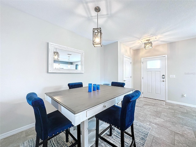 dining room with stone finish flooring, baseboards, and a textured ceiling