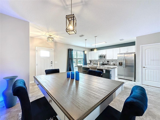 dining room featuring a textured ceiling and visible vents