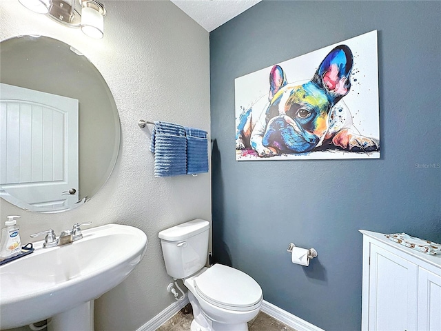 bathroom with baseboards, a sink, and toilet