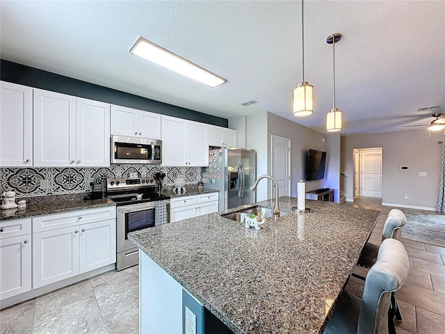 kitchen featuring tasteful backsplash, visible vents, a breakfast bar area, appliances with stainless steel finishes, and a sink