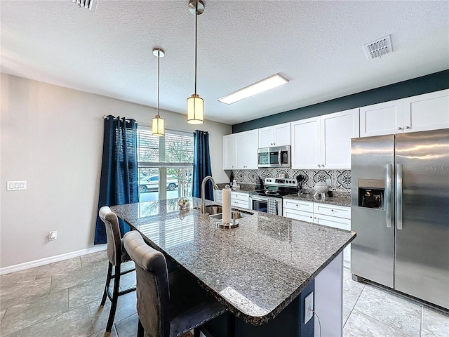 kitchen featuring tasteful backsplash, visible vents, appliances with stainless steel finishes, a sink, and an island with sink