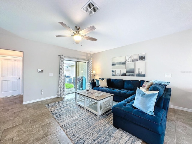 living room with baseboards, visible vents, a ceiling fan, and stone finish flooring