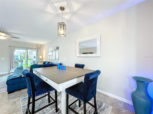 dining area featuring a ceiling fan, stone finish floor, and baseboards