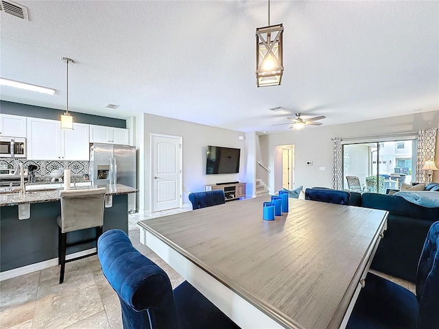 dining area featuring a ceiling fan, visible vents, stairway, and a textured ceiling