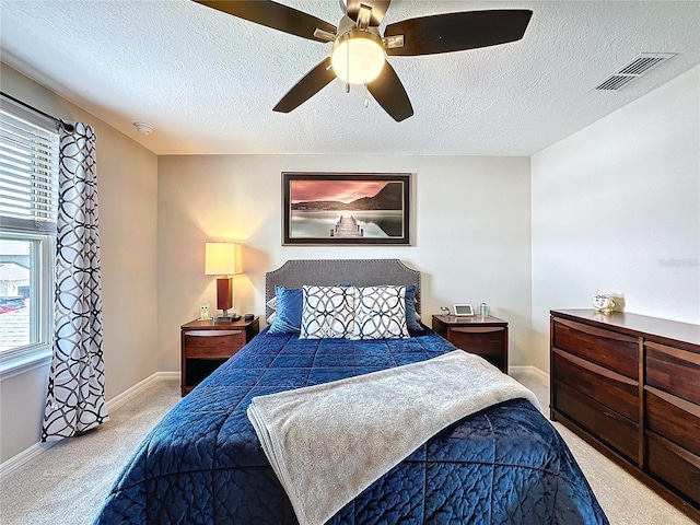 carpeted bedroom featuring baseboards, a textured ceiling, visible vents, and a ceiling fan