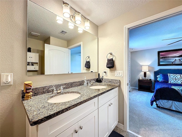 ensuite bathroom featuring a textured ceiling, ensuite bath, a sink, and visible vents