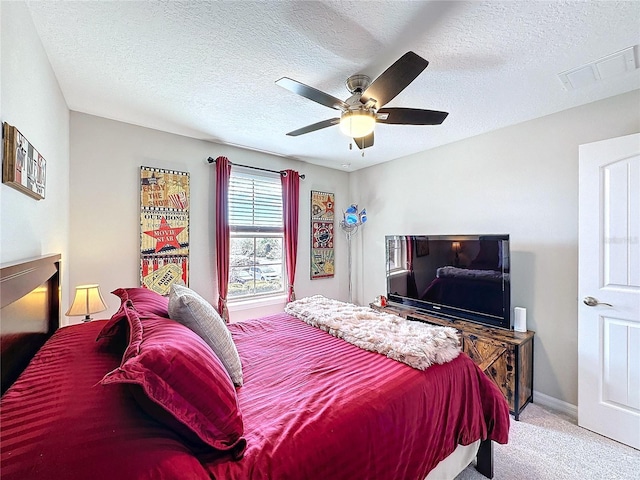 carpeted bedroom with a textured ceiling, baseboards, visible vents, and a ceiling fan