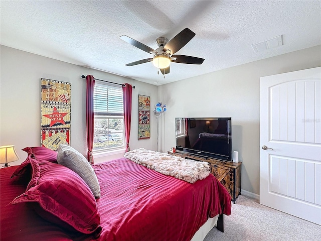 carpeted bedroom featuring a ceiling fan, baseboards, visible vents, and a textured ceiling