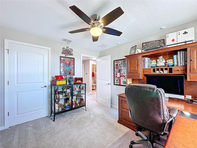 office space with light carpet, a ceiling fan, visible vents, and a textured ceiling