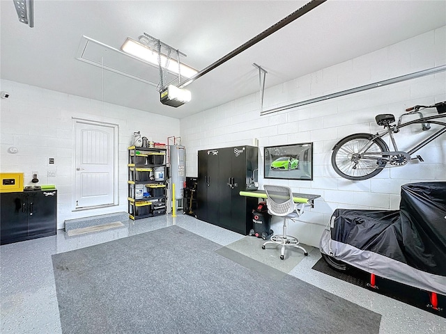 garage with concrete block wall, electric water heater, and a garage door opener