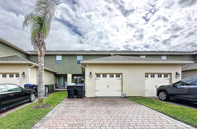 view of front facade with a garage, decorative driveway, and stucco siding