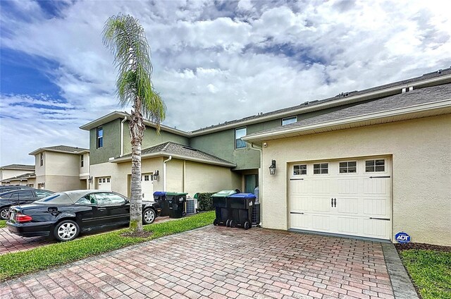 view of side of property with decorative driveway and stucco siding