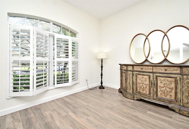 interior space featuring light wood-type flooring, multiple windows, and baseboards