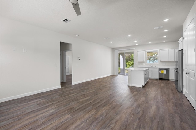 kitchen with white cabinets, dark wood finished floors, a kitchen island, open floor plan, and stainless steel appliances