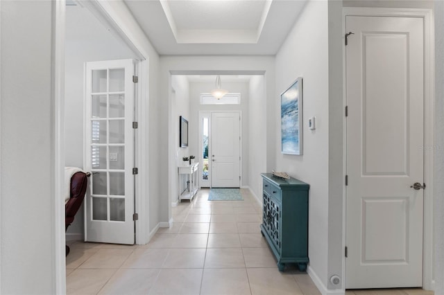 entryway with a raised ceiling, baseboards, and light tile patterned floors