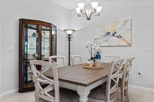 dining space featuring light tile patterned flooring, a notable chandelier, and baseboards