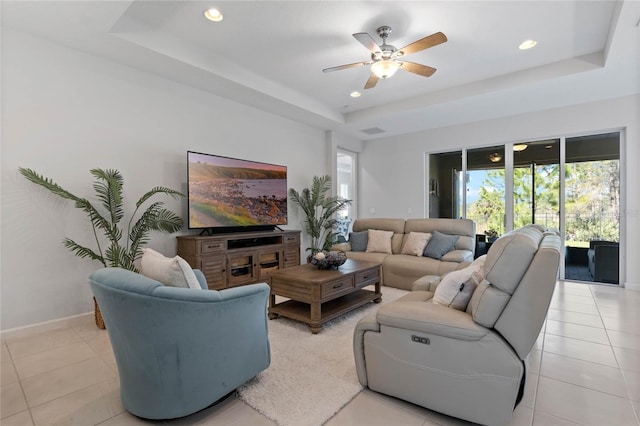 living area featuring light tile patterned floors, baseboards, a raised ceiling, and recessed lighting