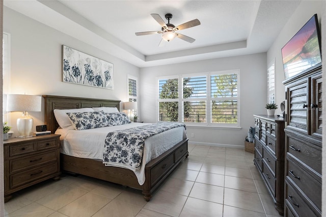 bedroom with light tile patterned floors, baseboards, a raised ceiling, and a ceiling fan