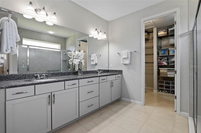 bathroom featuring a spacious closet, a sink, a shower stall, and double vanity