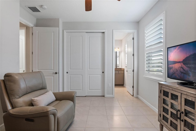 sitting room featuring baseboards, visible vents, a ceiling fan, and light tile patterned flooring