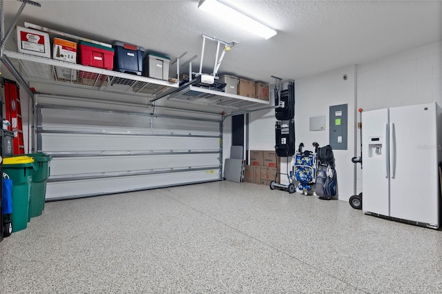 garage featuring electric panel, white fridge with ice dispenser, and a garage door opener