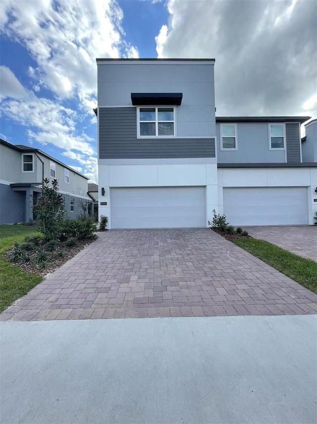 view of front facade with an attached garage, decorative driveway, and stucco siding