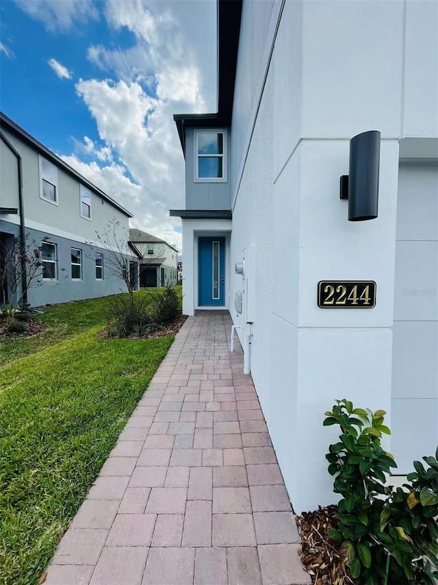 entrance to property with a yard and stucco siding