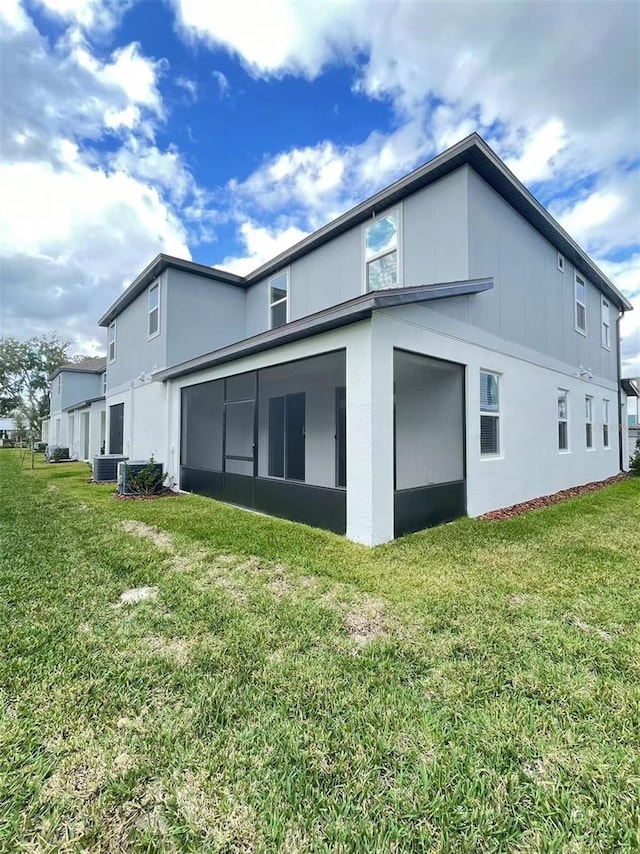 view of side of property featuring cooling unit, a lawn, and stucco siding