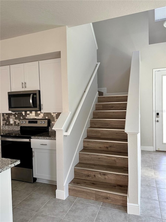 staircase featuring tile patterned flooring and baseboards