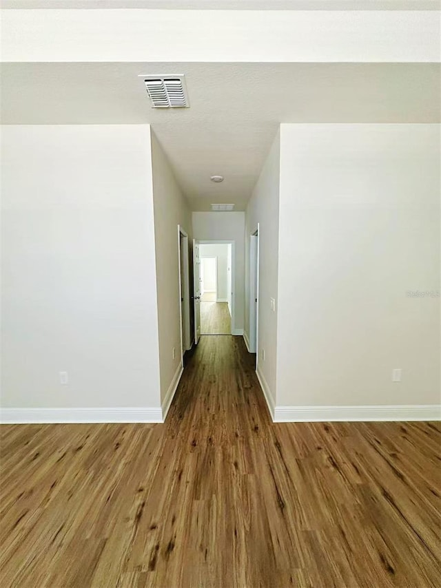 hallway featuring wood finished floors, visible vents, and baseboards