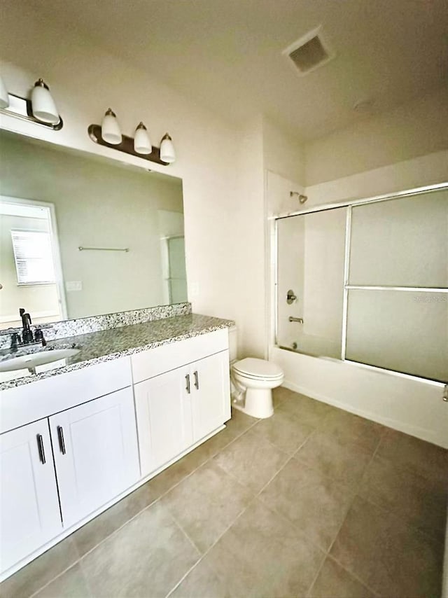 bathroom with visible vents, toilet, shower / bath combination with glass door, tile patterned floors, and vanity