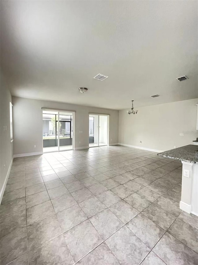 unfurnished living room with visible vents, baseboards, and an inviting chandelier