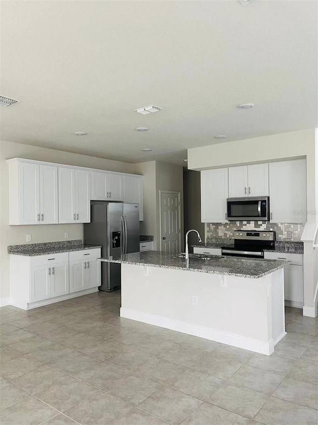 kitchen featuring appliances with stainless steel finishes, dark stone countertops, visible vents, and tasteful backsplash