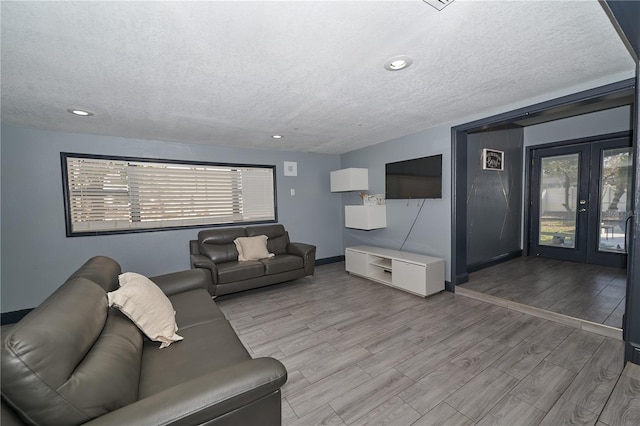 living room with a textured ceiling, french doors, plenty of natural light, and wood tiled floor