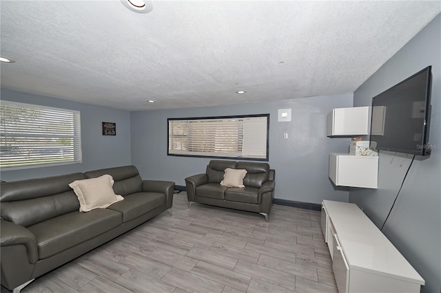 living area with light wood-style flooring, baseboards, a textured ceiling, and recessed lighting