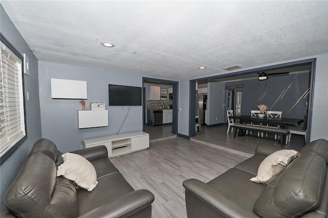 living area with recessed lighting, visible vents, a textured ceiling, and wood finished floors