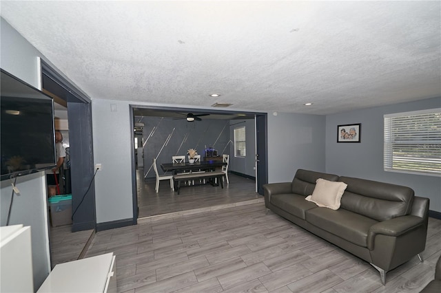 living area with wood tiled floor, visible vents, ceiling fan, and a textured ceiling